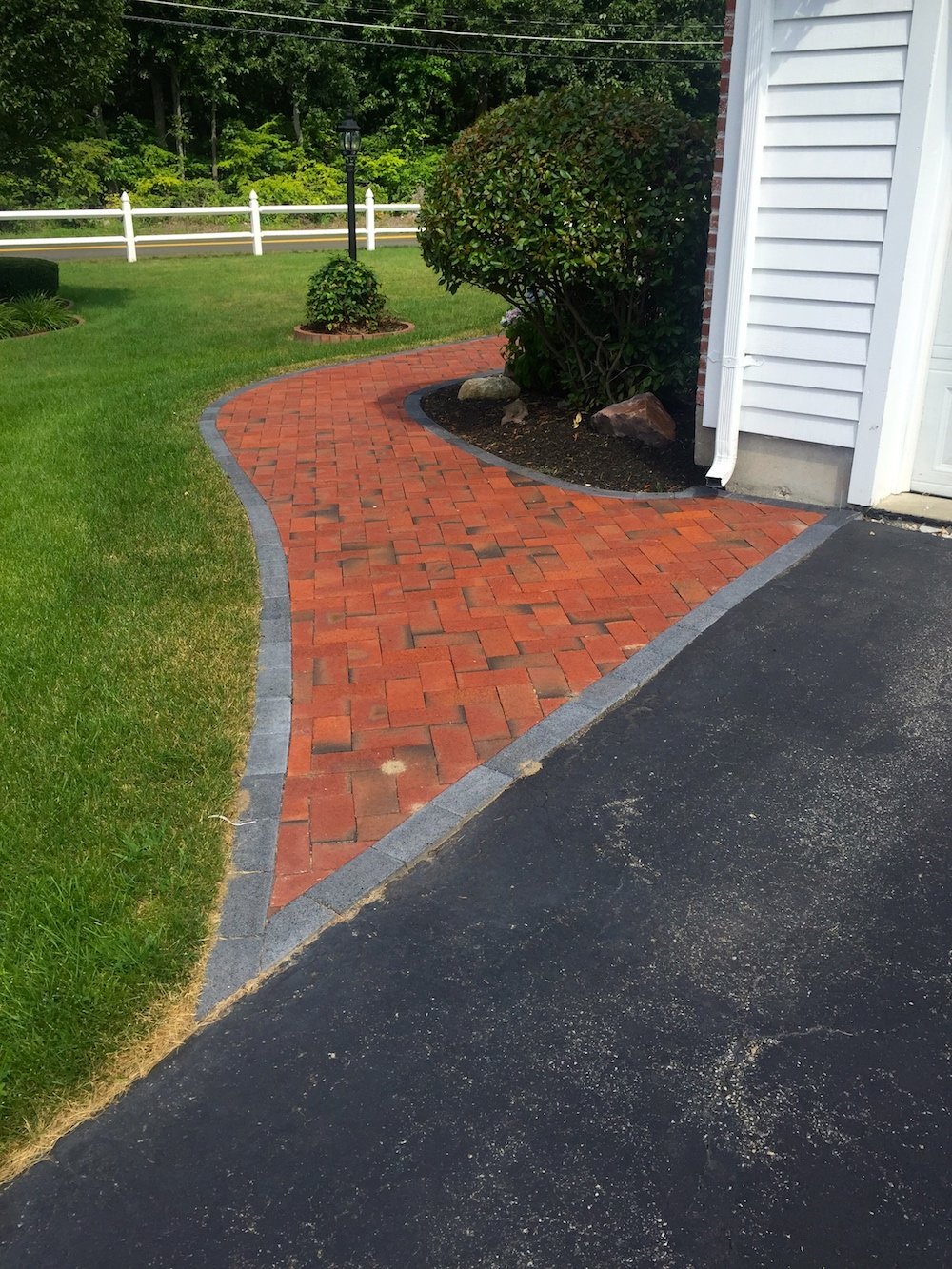 Curved red brick walkway with granite border edging