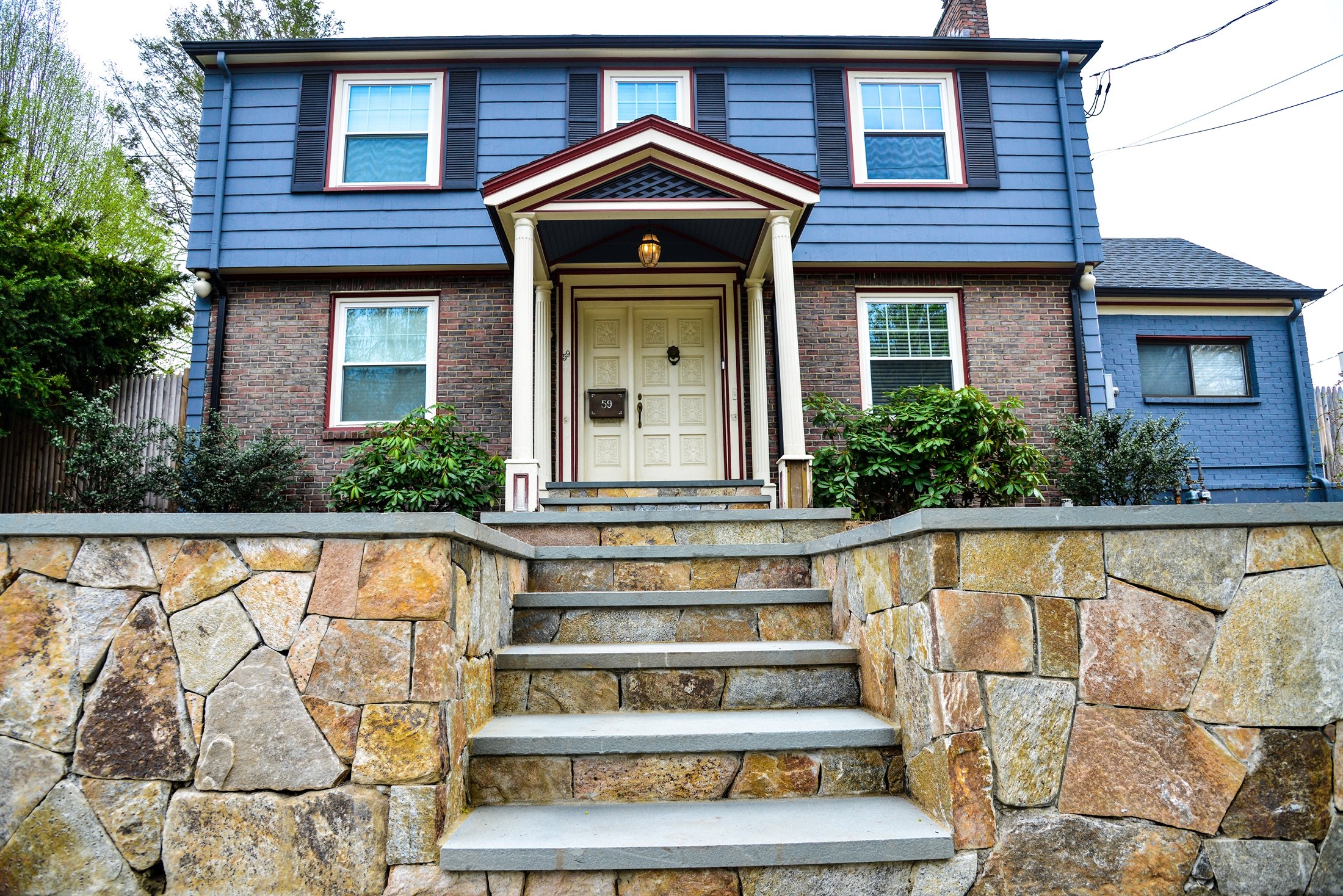 Colonial home with natural stone wall and entry steps