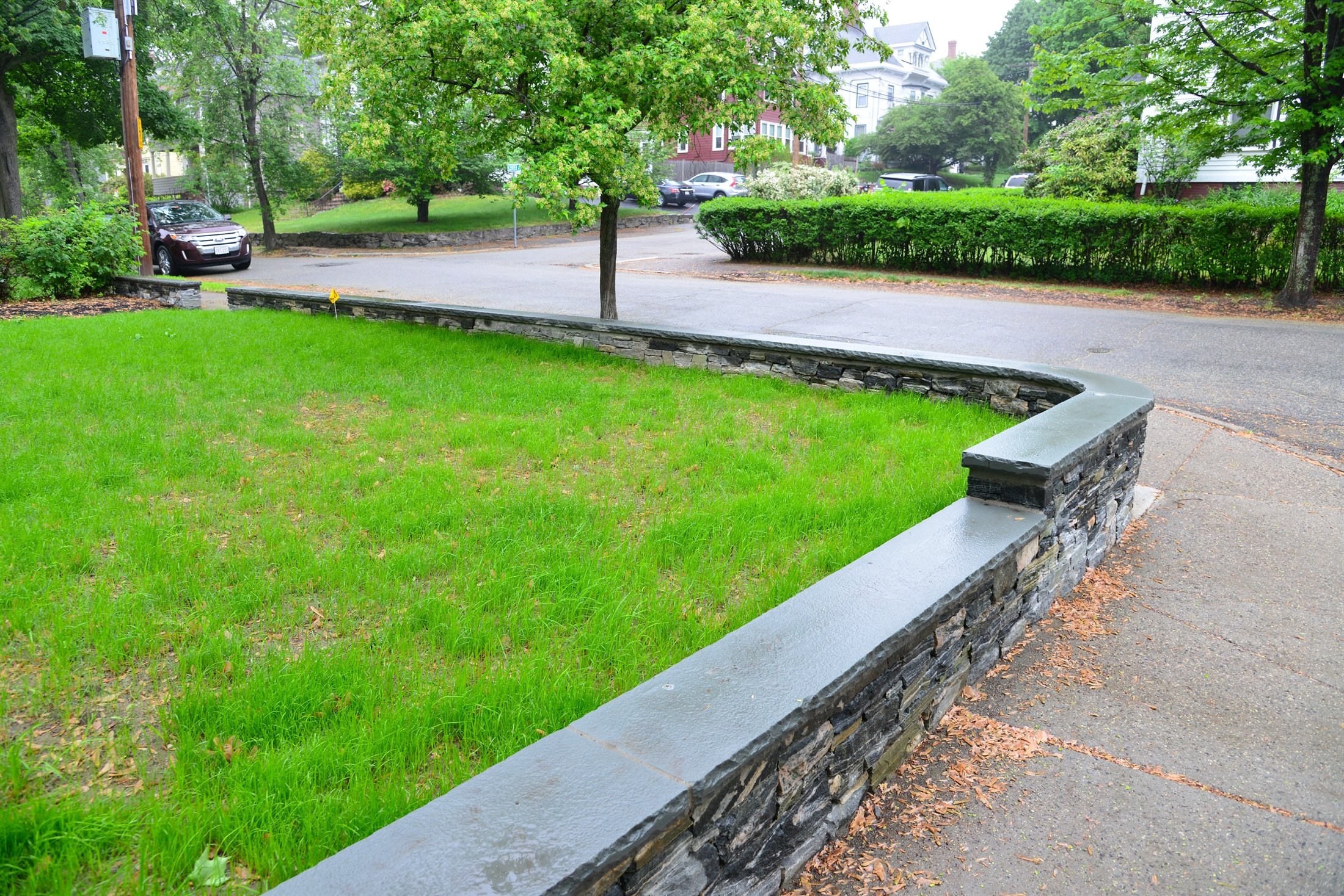 Low stone retaining wall with dark bluestone cap