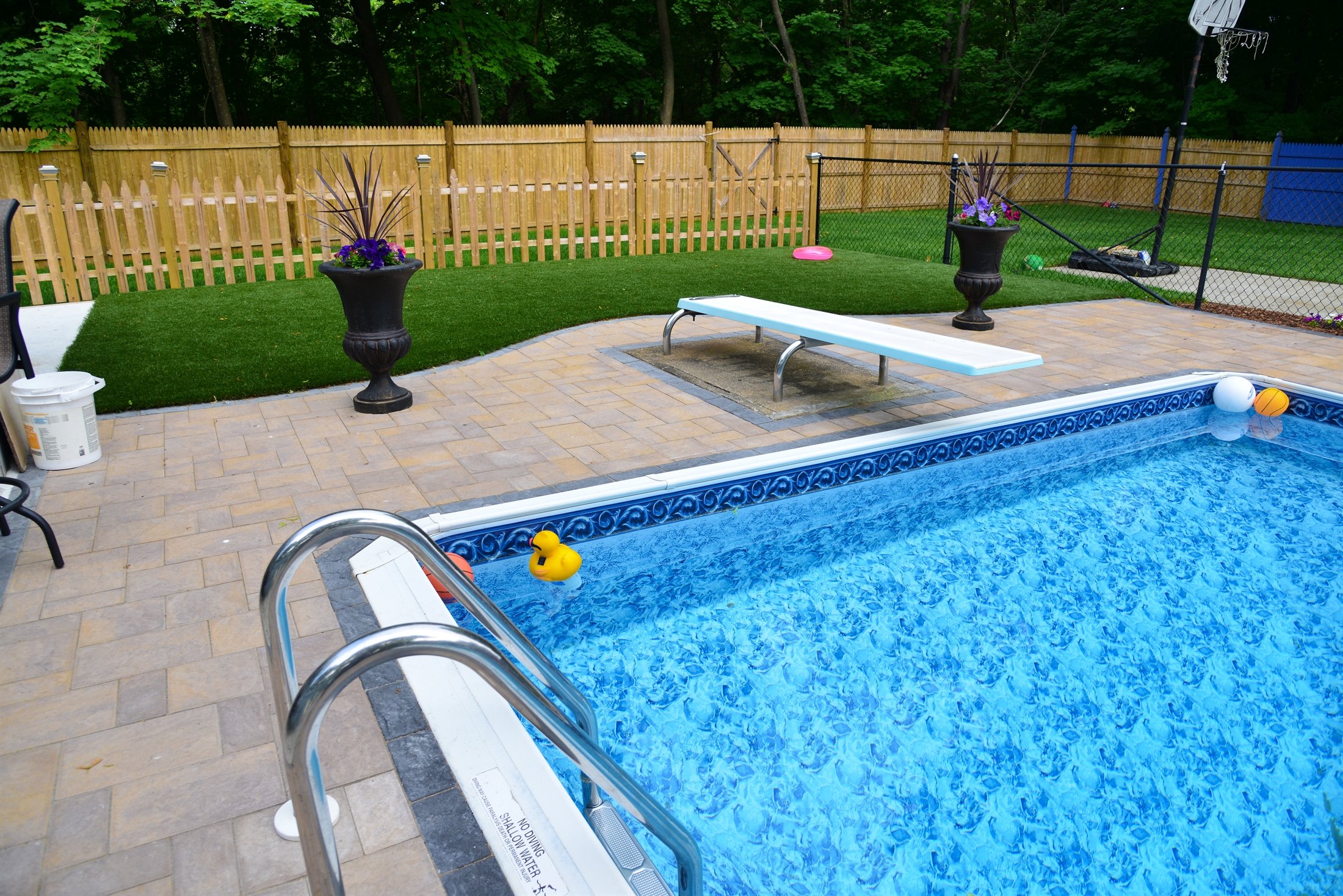 Paver patio surrounding in-ground pool with artificial turf