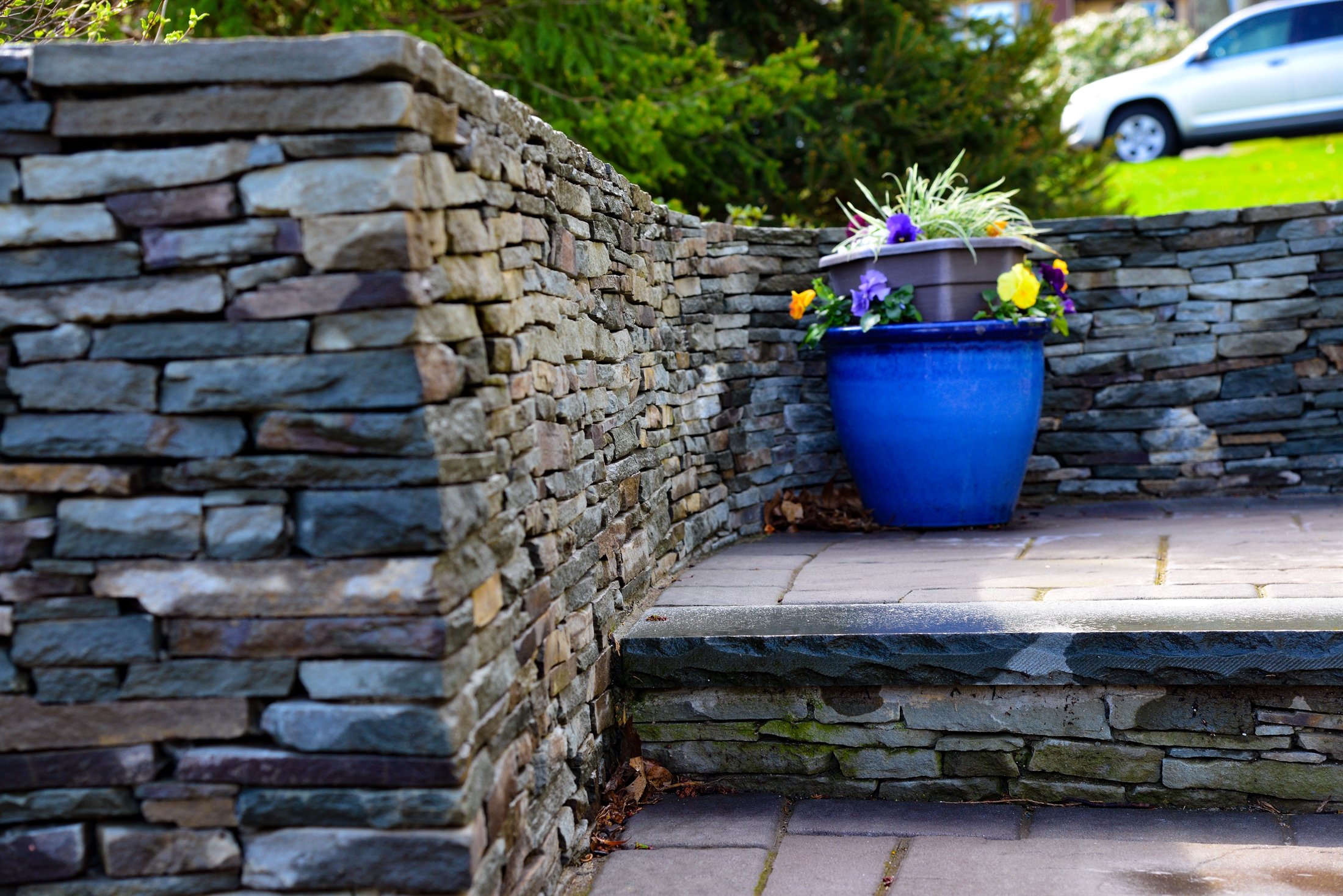 Dry-laid fieldstone retaining wall with blue planter detail